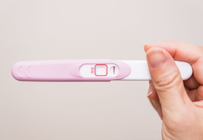 妊娠検査薬を持つ女性の手元